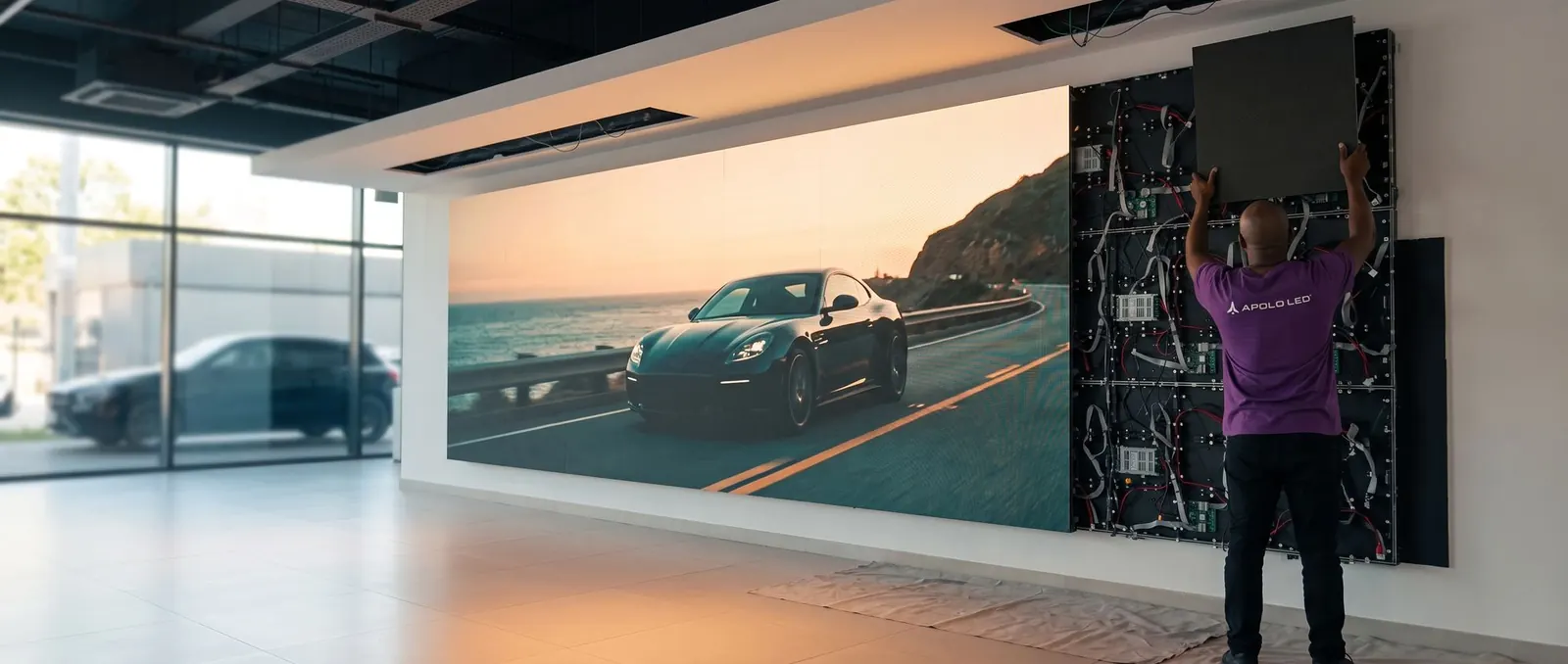 Técnico da Apolo LED instalando o último módulo de um painel de LED indoor em showroom de concessionária